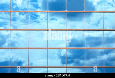 Splendidi cieli blu e nuvole si riflettono su grandi pannelli di vetro specchio della finestra dell'edificio Foto Stock