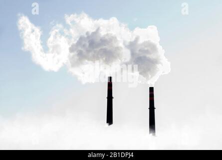 Pennacchi di fumo bianco che esce dai ciminiere contro i cieli soleggiati Foto Stock