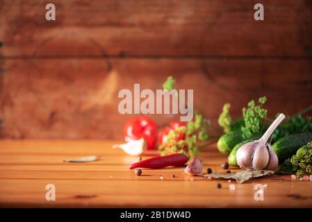 Ingredienti, spezie ed erbe per inscatolarsi cetrioli su sfondo di legno. Spazio di copia. Fiori di aneto, foglia di alloro, foglia di rafano, aglio, cetriolini Foto Stock