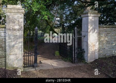Porta aperta in ghisa nera che conduce all'area del parco di Castle Ashby Gardens, Northamptonshire, Regno Unito Foto Stock