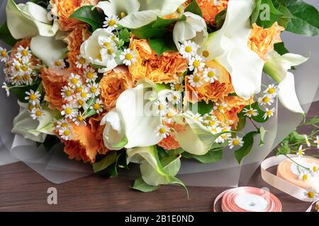 Primo piano di moda bouquet moderno di fiori diversi su sfondo di legno. Masterclass. Regalo per sposa in matrimonio, madre, donna. Romantica moda primaverile. Colori luminosi di sentimenti. Foto Stock