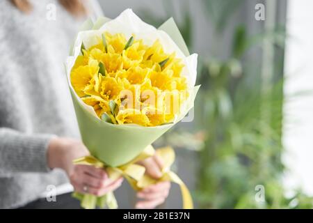 Narcissus. Bouquet di fiori di colore giallo in mano di donna. Il lavoro del fiorista in un negozio di fiori. Foto Stock