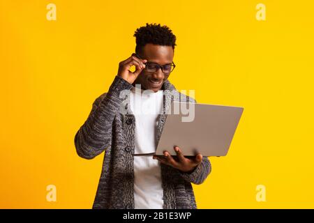 Programmatore uomo africano americano con portatile su giallo Foto Stock