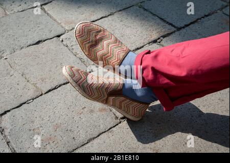 Primo piano di piedi alla moda di un uomo europeo irriconoscibile attraversato all'aperto su soleggiate pavimentazione in pietra Foto Stock