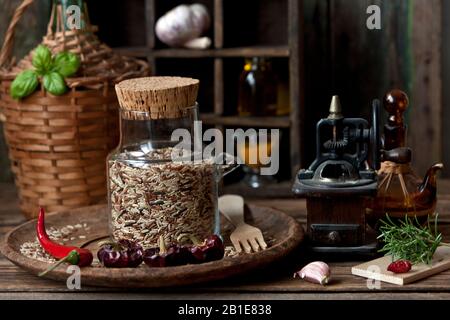 Primo piano di riso misto in bottiglia di vetro con aglio e peperoncino rosso caldo su fondo di legno Foto Stock