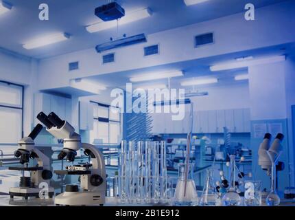 Laboratorio scientifico. Becher, provette e microscopio su tavolo di vetro in laboratorio. Foto Stock