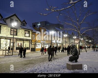 Vista della principale via dello shopping Storgata a Tromso Norvegia in una serata innevata a febbraio Foto Stock