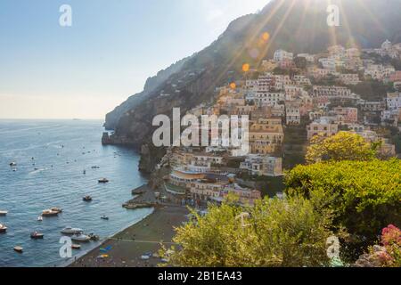 Fantastica vista sulla città di Positano e sul mare in un tramonto estivo. Raggi solari con riflessi lenti. Foto Stock