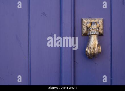 Porta di legno viola brillante con un bussare dorato a forma di mano. Estoi, Portogallo. Foto Stock
