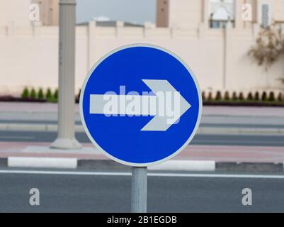 Freccia bianca sul cartello blu del traffico sulla strada Foto Stock