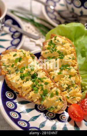 Uova strapazzate con erba cipollina su pane croccante fresco, colazione fatta in casa Foto Stock