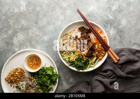 Ciotola di insalata tradizionale vietnamita noodle - Bun Bo Nam Bo, con manzo, noodle di riso, erbe fresche, verdure sottaceto e salsa di pesce Foto Stock