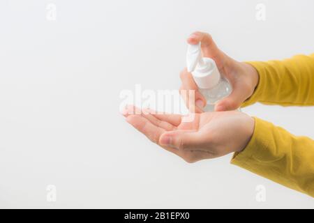 Mani femminili usando la mano di lavaggio con L'alcool Sanitizer isolano su una priorità bassa bianca. Promuovere l'uso delle persone per proteggersi dall'infezione da virus Foto Stock