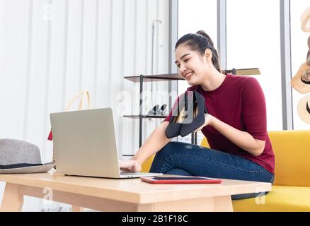 Happy Asian internet influencer rivedere le sue nuove scarpe blu scuro scarpe con tacco alto da streaming online. Foto Stock