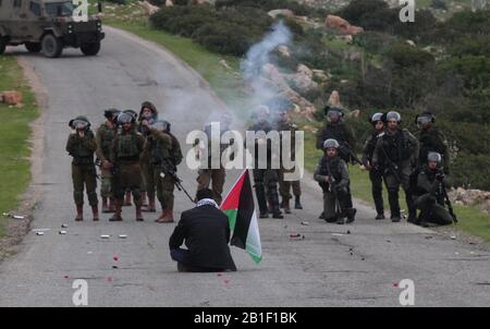 (200225) -- TUBIAS, 25 febbraio 2020 (Xinhua) -- un uomo palestinese siede di fronte ai soldati israeliani durante gli scontri al checkpoint di Tayasir vicino alla città di Tubas della Cisgiordania, il 25 febbraio 2020. Decine di manifestanti palestinesi hanno battuto martedì con soldati israeliani in un blocco stradale dell'esercito israeliano su una strada che porta alla Valle del Giordano in Cisgiordania, hanno detto fonti mediche e di sicurezza. (Foto Di Nidal Eshtayeh/Xinhua) Foto Stock