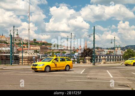 Un taxi giallo si trova sulla piazza vicino all'argine del Danubio nel centro di Budapest e aspetta i suoi passeggeri. Giornata di sole intensa e luminosa Foto Stock