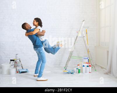 Giovane coppia afroamericana abbracciando. Vicino a scala e secchi di vernice Foto Stock