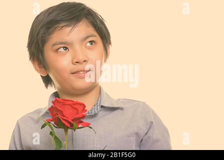 Close up carino ragazzo giapponese azienda red rose e pensare Foto Stock