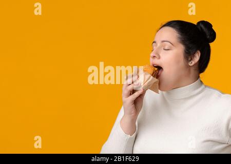 Hungry Plus Size Girl Eating Burger Con Occhi Chiusi Foto Stock