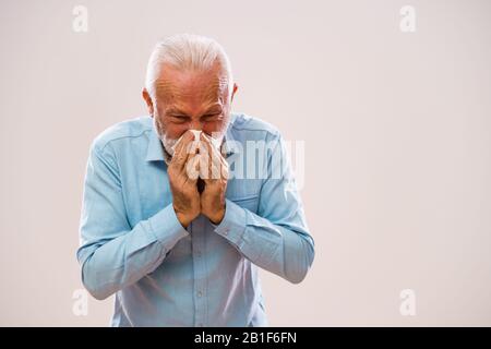 Ritratto di uomo anziano che sta soffiando naso. Foto Stock