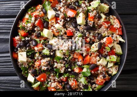 Insalata di quinoa vegetariana con avocado fresco, peperoni, pomodori e fagioli neri da vicino in un piatto sul tavolo. Vista dall'alto orizzontale Foto Stock