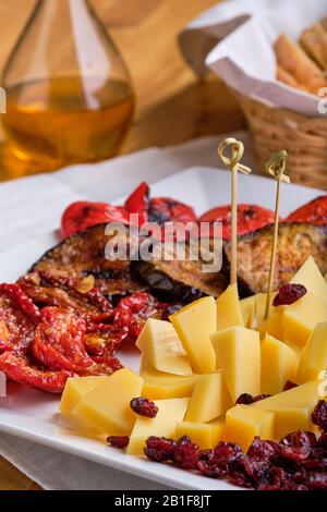 Vista ravvicinata della serie di antipasti vari per il vino - formaggio, pomodori secchi, melanzane arrosto, peperone, impasti e mirtilli secchi Foto Stock