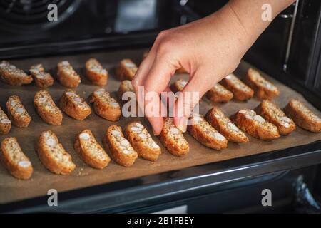 Persona che prende cantuccini fatti in casa da forno vassoio Chiudi. Foto Stock