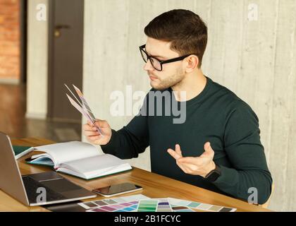 Freelance Designer Che Lavora Con I Campioni Di Colore Seduti In Ufficio Foto Stock