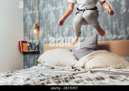 dettaglio di una piccola ragazza gambe saltando in alto nel suo letto genitori, concetto di stile di vita a casa e infanzia felice Foto Stock