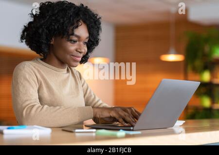 Blogger femminile che lavora al bar, digitando sul portatile Foto Stock