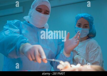 mettere a fuoco le mani dei chirurghi pediatrici nei guanti, eseguire un'operazione su un piccolo paziente, la fase di trattamento del campo chirurgico bef Foto Stock