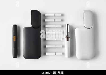 Nuova generazione, nero e bianco, due sigarette elettroniche e due batterie aperte, sette bastoni termici isolati su bianco. Riscaldamento del tabacco. Templat Foto Stock