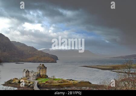 EILEAN DONAN CASTELLO LOCH DUICH DORNIE SCOZIA IN INVERNO RACCOLTA NUVOLE TEMPESTA CON NEVISCHIO E NEVE SULLE MONTAGNE Foto Stock