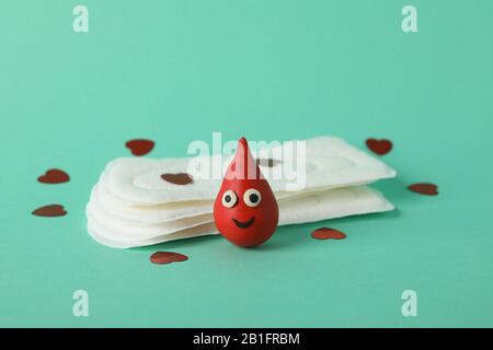 Assorbenti igienici, gocce decorative di sangue e piccoli cuori su sfondo di menta, closeup Foto Stock