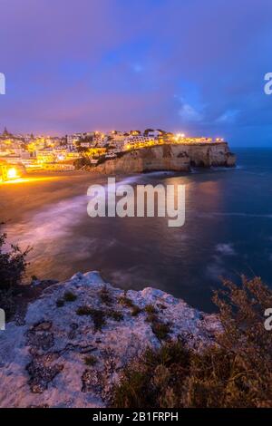 Vista delle luci del villaggio di Carvoeiro e la sua spiaggia a ore blu. Lagoa, Algarve, Portogallo, Europa. Foto Stock