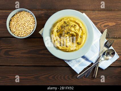 Lenten food: Crema pea porridge o zuppa guarnita con semi di zucca e lino piatto su tavola di legno, closeup, copia spazio, dall'alto vista. D. Rapido Foto Stock