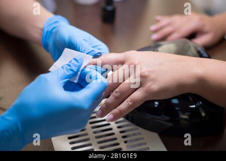 Capitano donna manicure. La ragazza non manicure in un salone di bellezza. Sotto una lampada da tavolo, in un ufficio, closeup mani e unghie di verniciatura Foto Stock