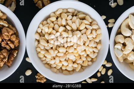 concetto di superfood, cedro, noci, cashew noci in una piastra su uno sfondo nero Foto Stock