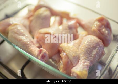 Cosce di pollo crude in un piatto di cottura di vetro Foto Stock