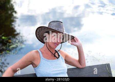 Una donna in un cappello da cowboy, in natura. Vicino all'acqua. Foto Stock