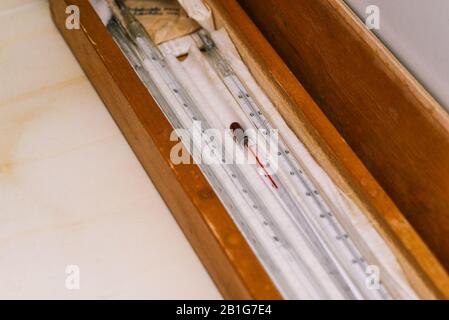 Termometro a mercurio in vetro in una custodia in legno. Vecchio strumento per la misurazione della temperatura dei liquidi e l'uso in laboratorio Foto Stock