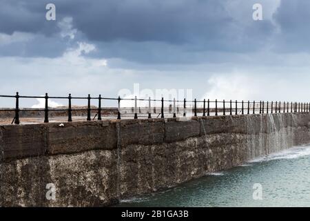 Le grandi onde passano sopra il breakwater concreto sotto il cielo tempestoso. Spiaggia Di Montazah, Alessandria, Egitto Foto Stock