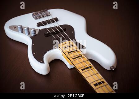 Chitarre White Electric Bass Con Collo D'Acero, Sottaceti Neri E Inserti Black Block Su Un Semplice Sfondo In Legno Foto Stock