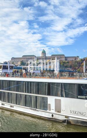 Budapest, Ungheria - 6 novembre 2019: Parte di un'enorme nave da crociera sul Danubio nella capitale ungherese. Castello di Buda sullo sfondo. Mezzi di trasporto non rispettosi dell'ambiente. Foto verticale. Foto Stock