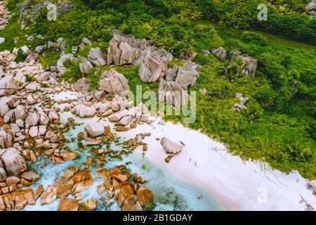 La Digue, Seychelles. Veduta aerea della spiaggia appartata nascosta nella giungla. Spiaggia di sabbia bianca con acque turchesi dell'oceano e pittoresche rocce di granito Foto Stock