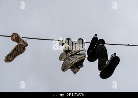 Scarpe da ginnastica appese su un cielo nuvoloso luminoso, stile di vita urbano simbolo dell'arte della città Foto Stock