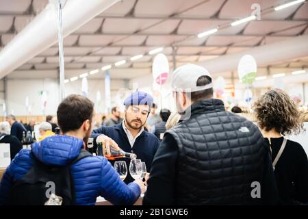 Strasburgo, Francia - 16 febbraio 2020: Uomo francese con berretto blu che versa vino ai clienti del vino francese Vignerons inglese indipendente: Produttori indipendenti di vino della Francia fiera del vino per privato Foto Stock