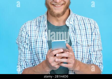 Closeup bearded giovane uomo utilizzare moderno smartphone sorriso SMS messaggio chat online Foto Stock
