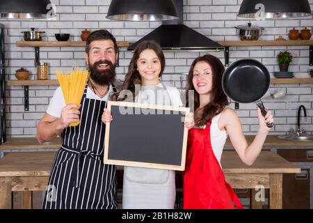 famiglia accogliente in cucina. cucina sana a casa. chef bambino con i genitori. papà e mamma che insegnano a cucinare alla figlia. buona giornata di famiglia. assistenza e supporto reciproci. copia spazio. Foto Stock