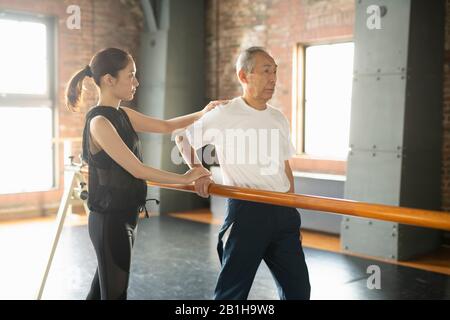 Uomo anziano in fase di riabilitazione esercizi a piedi con istruttore Foto Stock